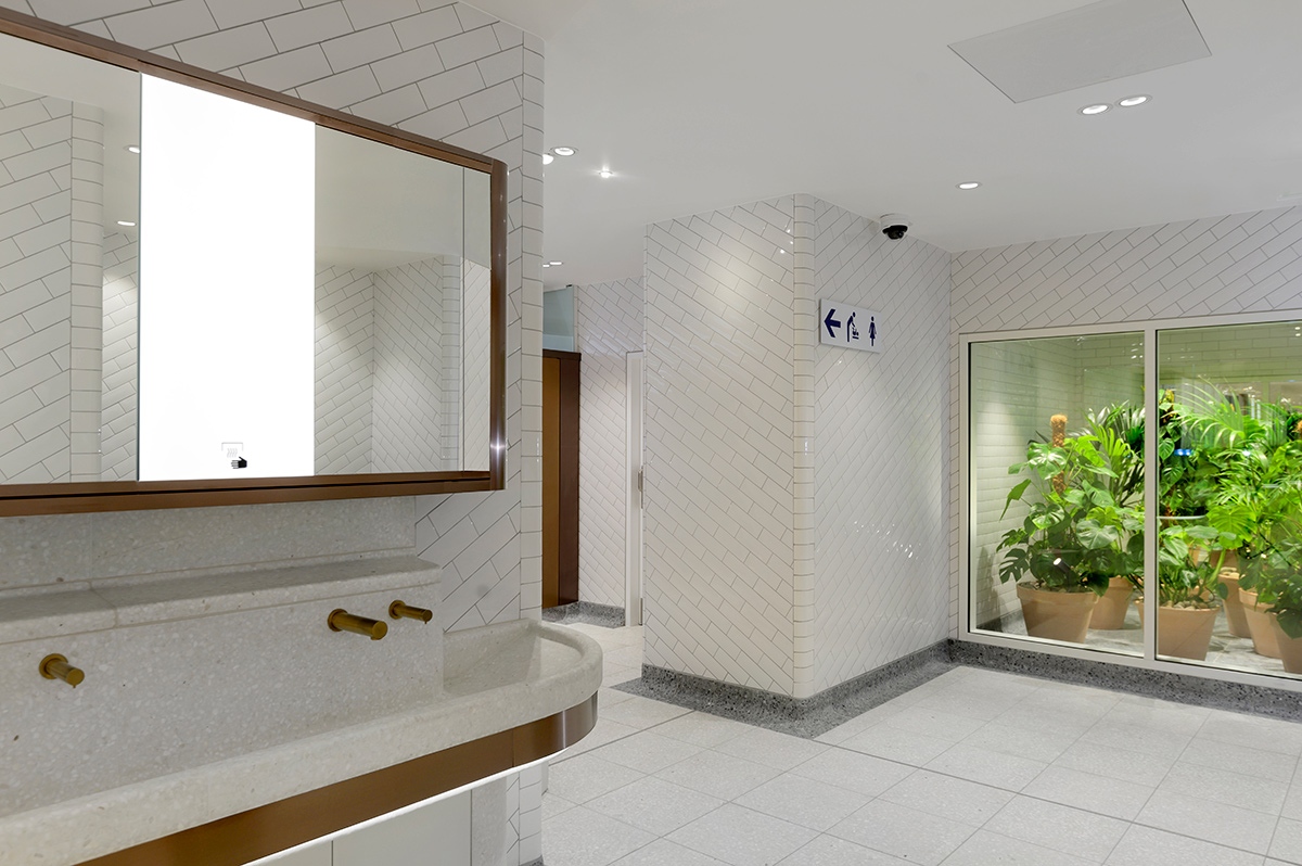 Interior of upgraded WCs Victoria Station, London showing bronze PVD stainless steel taps with matching mirror frame and horizontal banding around communal basin. Interior of upgraded WCs Victoria Station, London showing bronze PVD stainless steel taps with matching mirror frame and horizontal banding around communal basin.