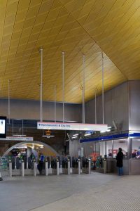 Showing the gold, or brass-coloured, anodised aluminium diagonally-set ceiling panels to the Wood Lane Underground Station, London. Architectural design by Ian Ritchie Architects. Ceiling by John Desmond Ltd.